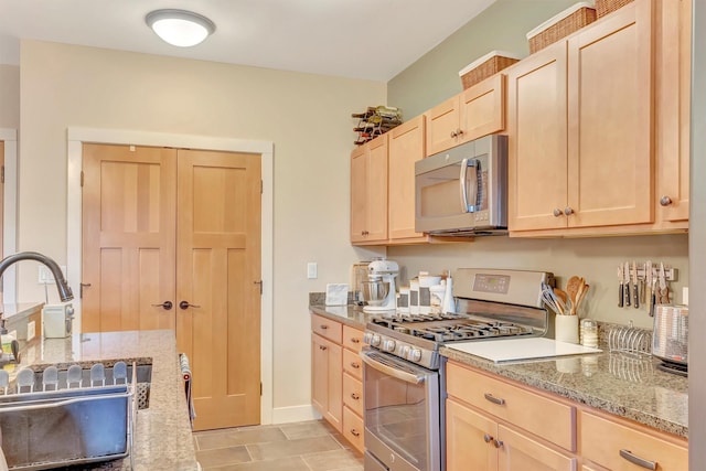 kitchen featuring a sink, light brown cabinetry, light stone countertops, and stainless steel appliances