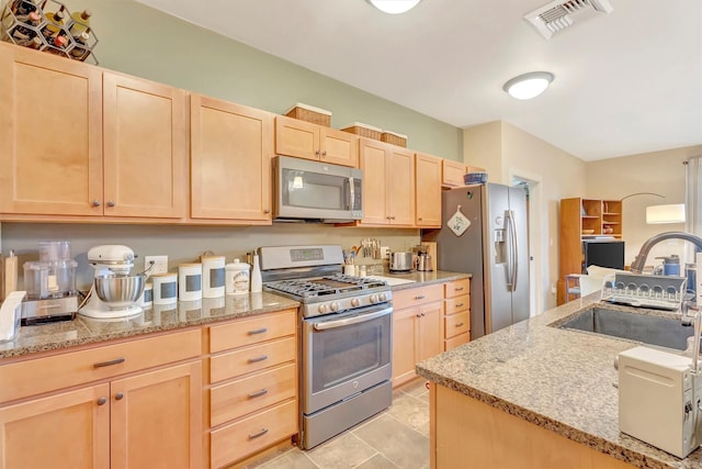 kitchen with visible vents, appliances with stainless steel finishes, a sink, light stone counters, and light brown cabinets