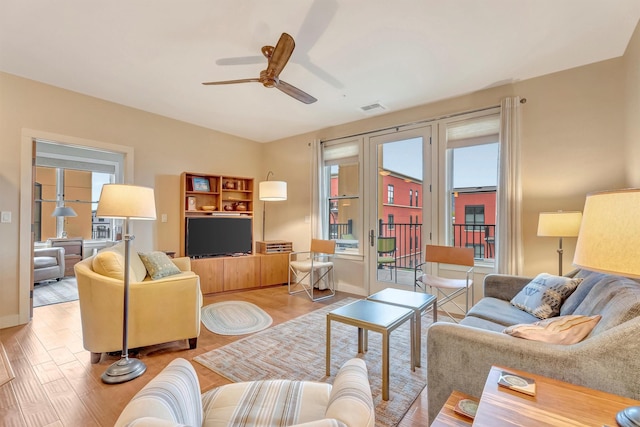 living room with a ceiling fan, visible vents, a healthy amount of sunlight, and wood finished floors