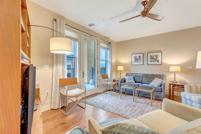 living area with baseboards, ceiling fan, light wood-type flooring, and visible vents