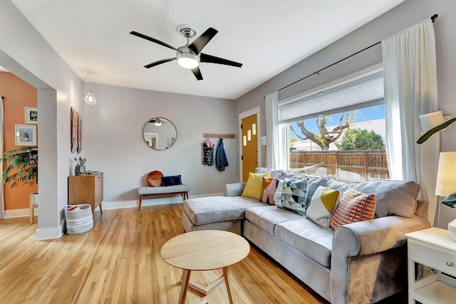 living room featuring baseboards, ceiling fan, and wood finished floors
