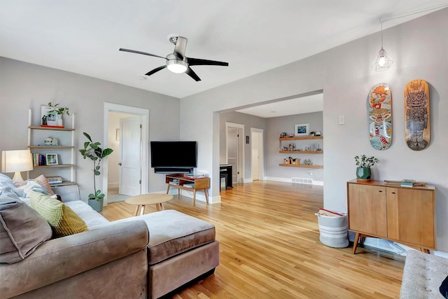 living area featuring baseboards, a ceiling fan, and light wood finished floors