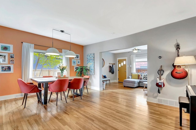 dining space with light wood-style floors, a ceiling fan, baseboards, and visible vents