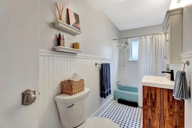 bathroom with shower / bathtub combination with curtain, toilet, wainscoting, and vanity