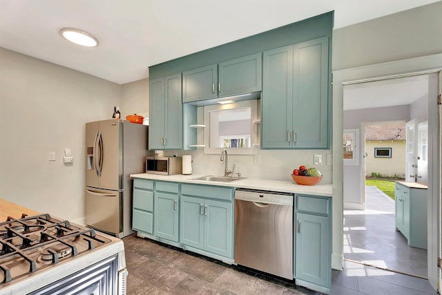 kitchen featuring appliances with stainless steel finishes, tasteful backsplash, open shelves, a sink, and light countertops