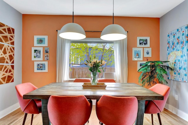 dining space featuring baseboards and light wood-type flooring