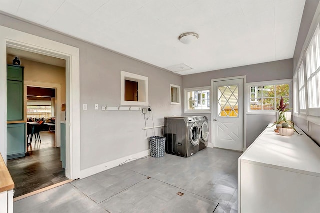 laundry area with baseboards, laundry area, plenty of natural light, and washer and clothes dryer