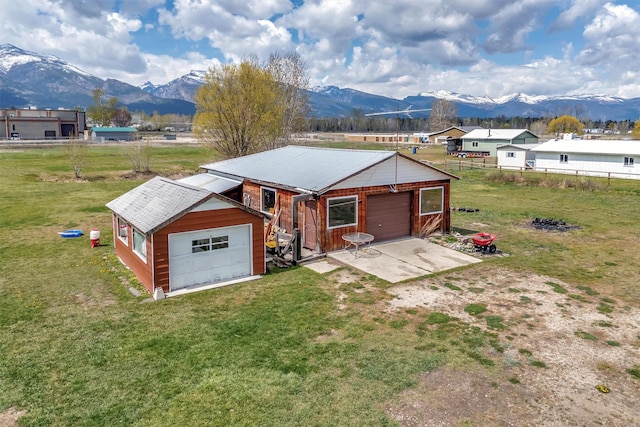 back of property featuring fence, driveway, an outbuilding, and a mountain view