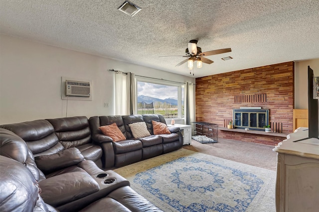 living area featuring a ceiling fan, visible vents, a large fireplace, a wall mounted air conditioner, and carpet floors