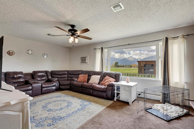 living room featuring a wall mounted air conditioner, carpet floors, a textured ceiling, a ceiling fan, and visible vents