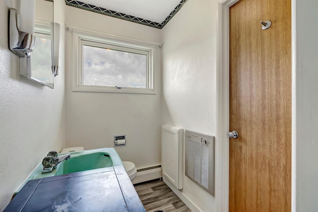 bathroom featuring a sink, a baseboard radiator, toilet, and wood finished floors
