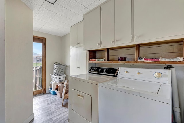 clothes washing area with light wood finished floors, cabinet space, and washer and dryer
