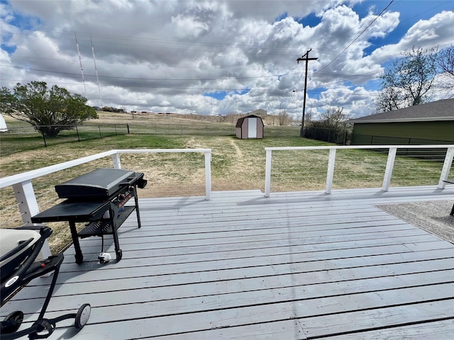 wooden deck featuring a fenced backyard, a shed, a rural view, a lawn, and an outbuilding