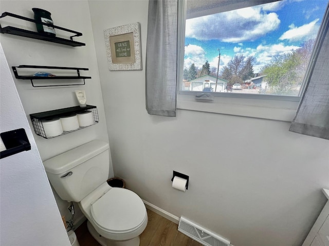 bathroom with plenty of natural light, toilet, wood finished floors, and visible vents