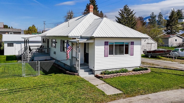 bungalow featuring a gate, a front lawn, fence, and metal roof