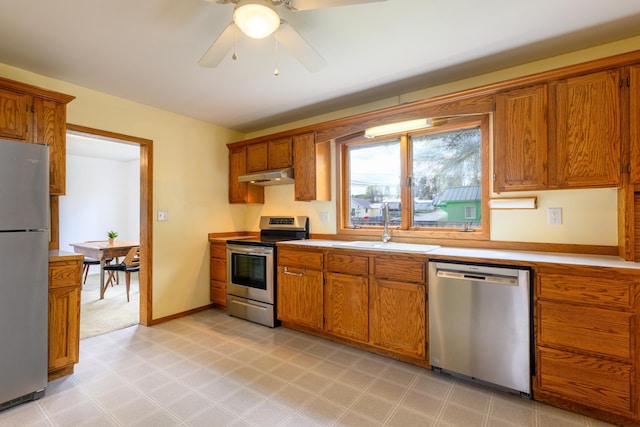 kitchen with a sink, stainless steel appliances, brown cabinets, and under cabinet range hood