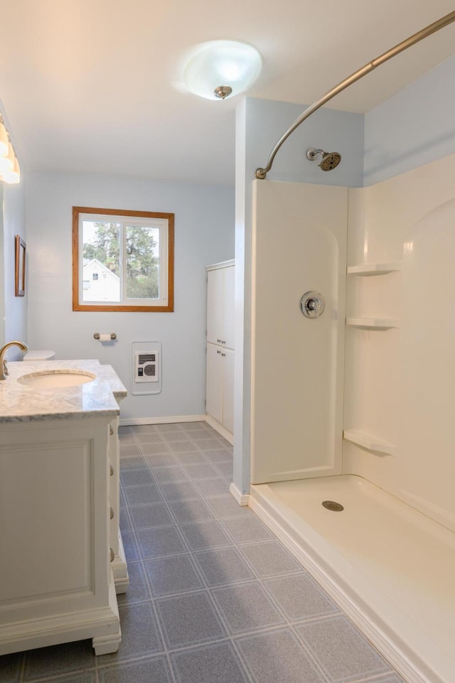 bathroom with vanity, baseboards, and a shower