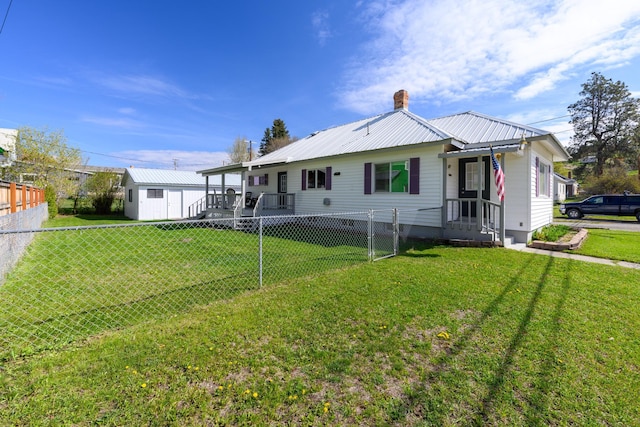 back of property featuring a fenced backyard, a yard, a chimney, and metal roof