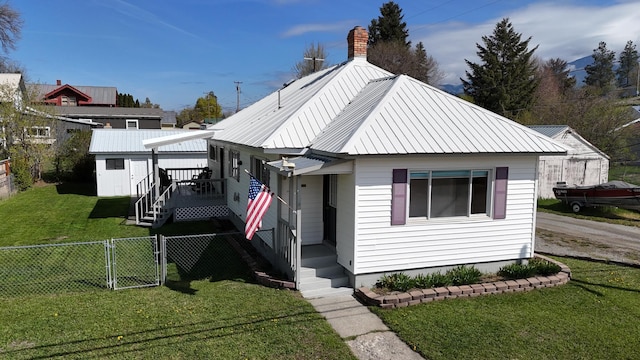 bungalow-style home featuring a front yard, a fenced backyard, a gate, a chimney, and metal roof