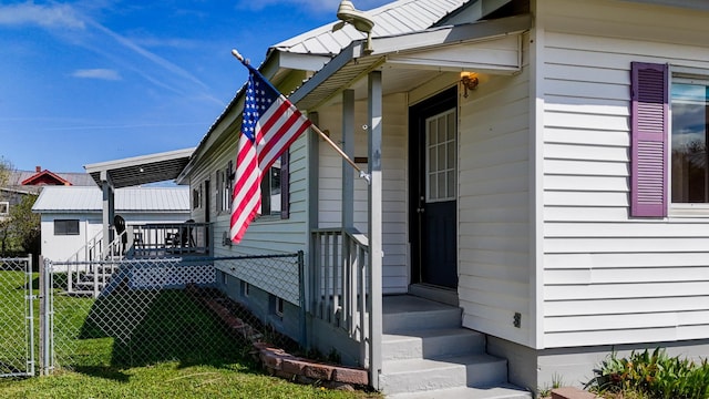 doorway to property featuring a porch, a lawn, and fence