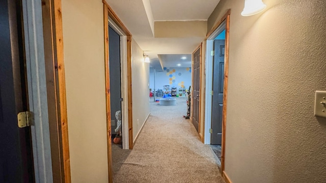hall with baseboards, carpet, and a textured wall