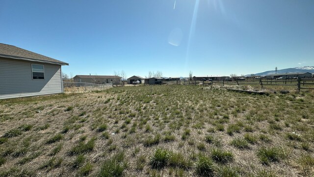 view of yard with fence, a mountain view, and a rural view