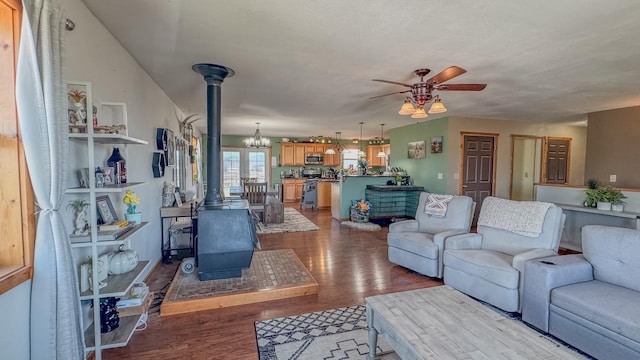 living room with a wood stove, a ceiling fan, and wood finished floors