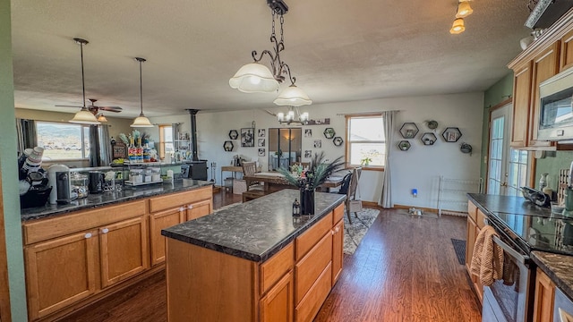kitchen featuring appliances with stainless steel finishes, a center island, a textured ceiling, and dark wood-type flooring