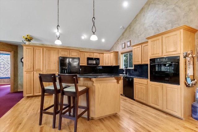 261 Green Briar Trl, Eureka, MT 59917 - kitchen featuring a kitchen island, light brown cabinets, a kitchen breakfast bar, high vaulted ceiling, and black appliances