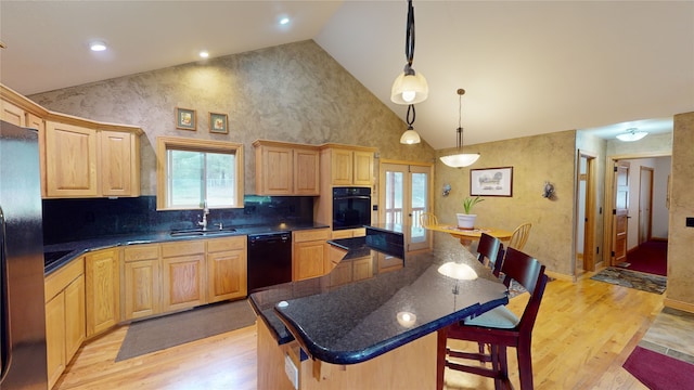 261 Green Briar Trl, Eureka, MT 59917 - kitchen with light brown cabinetry, a spacious island, a sink, black appliances, and light wood-style flooring