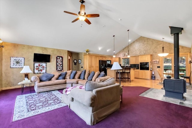 261 Green Briar Trl, Eureka, MT 59917 - living room with ceiling fan, light colored carpet, a wood stove, high vaulted ceiling, and baseboards