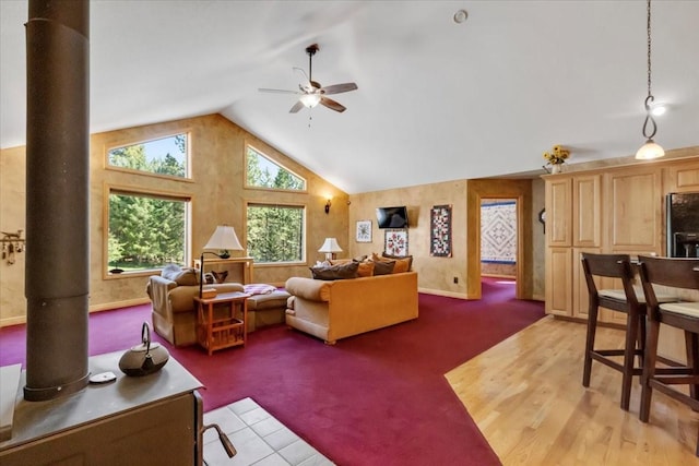 261 Green Briar Trl, Eureka, MT 59917 - living area with a ceiling fan, light colored carpet, a wood stove, vaulted ceiling, and baseboards