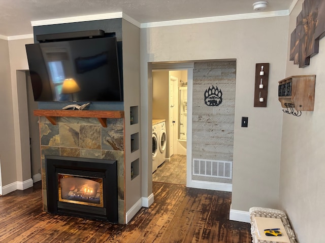living room featuring visible vents, ornamental molding, wood-type flooring, and washing machine and clothes dryer