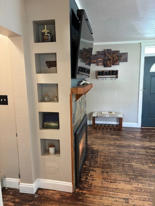 foyer with baseboards, a fireplace, a textured ceiling, and wood finished floors