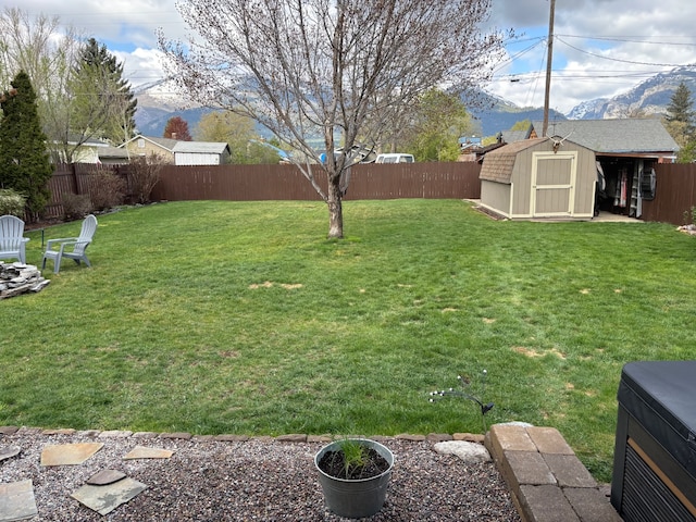 view of yard with a fenced backyard, a mountain view, an outbuilding, and a shed