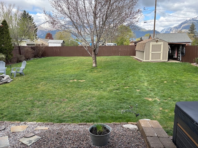 view of yard with a storage shed, a mountain view, an outdoor structure, and a fenced backyard