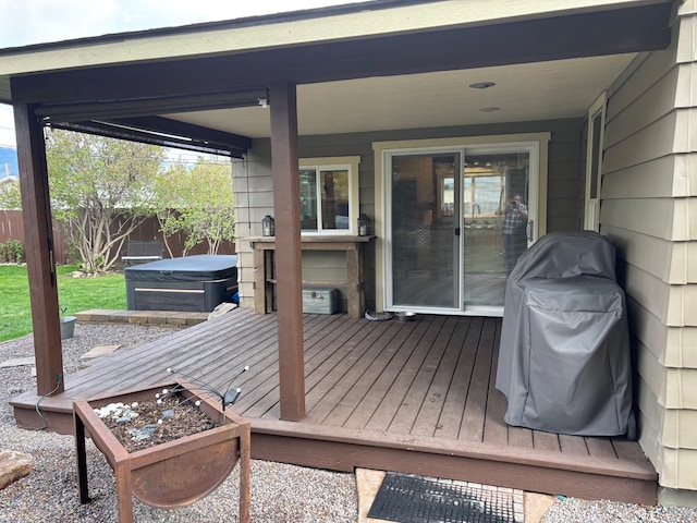 wooden deck featuring a hot tub, fence, and area for grilling