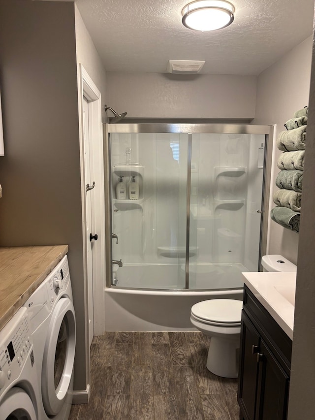 full bathroom featuring wood finished floors, a textured ceiling, washing machine and dryer, and toilet