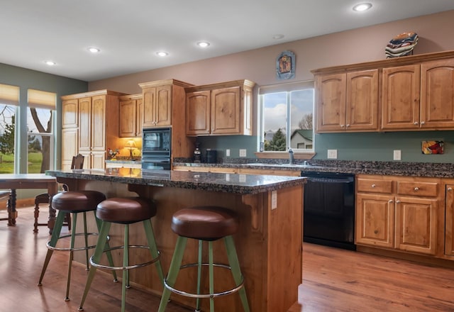kitchen with a kitchen breakfast bar, a sink, black appliances, and a center island