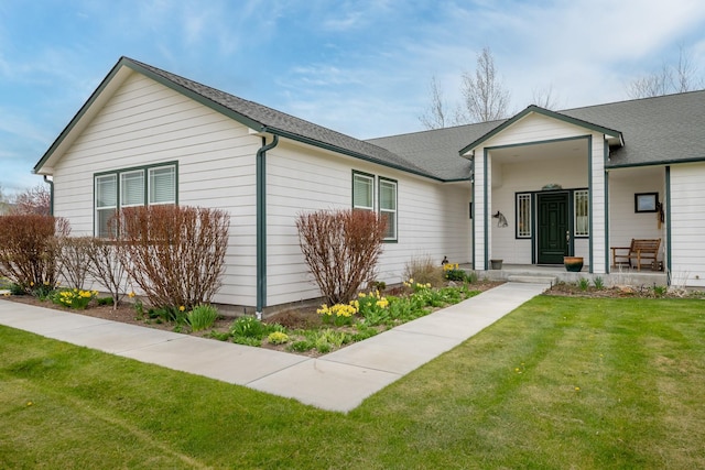 ranch-style house featuring roof with shingles and a front lawn