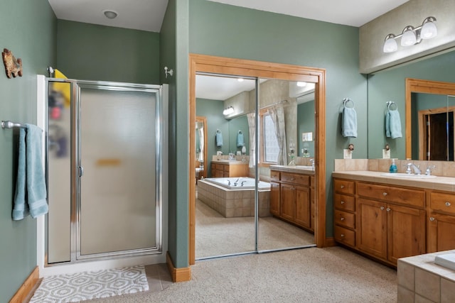 full bathroom featuring two vanities, a sink, a garden tub, and a stall shower