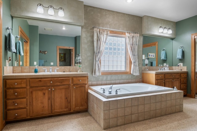full bathroom featuring vanity, speckled floor, and a bath