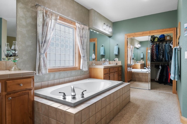 bathroom featuring a walk in closet, a bath, and vanity
