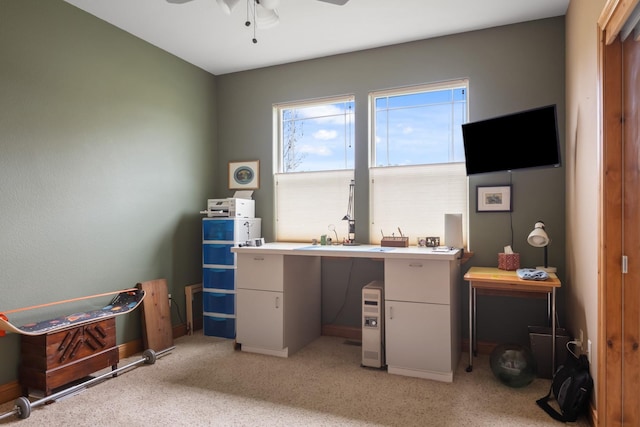office space featuring baseboards, a ceiling fan, and light colored carpet