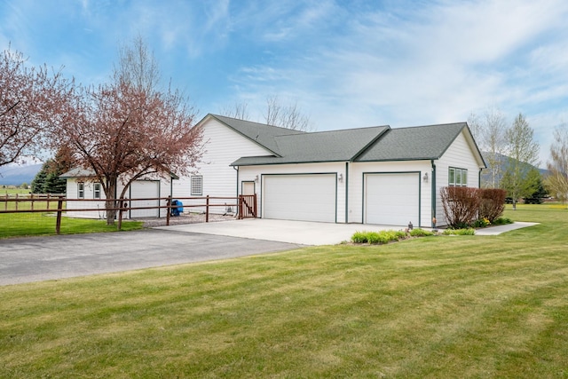 view of side of home with fence, a shingled roof, a garage, a lawn, and driveway