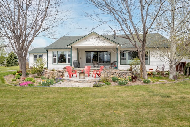rear view of house featuring a lawn, a patio, a fire pit, and roof with shingles