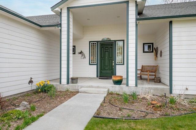 entrance to property with a porch and a shingled roof
