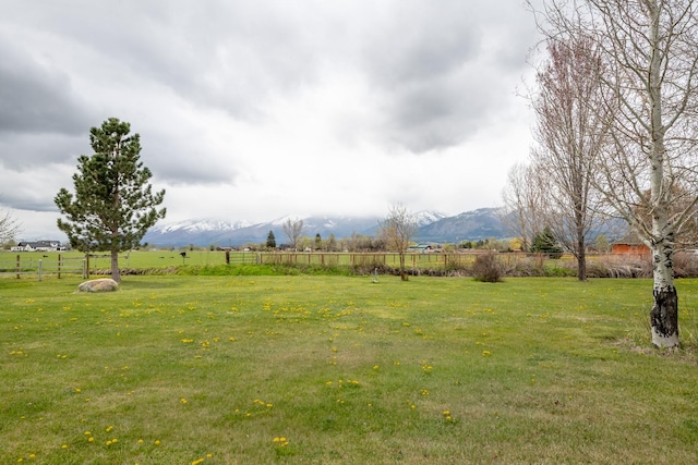view of yard featuring a mountain view, fence, and a rural view
