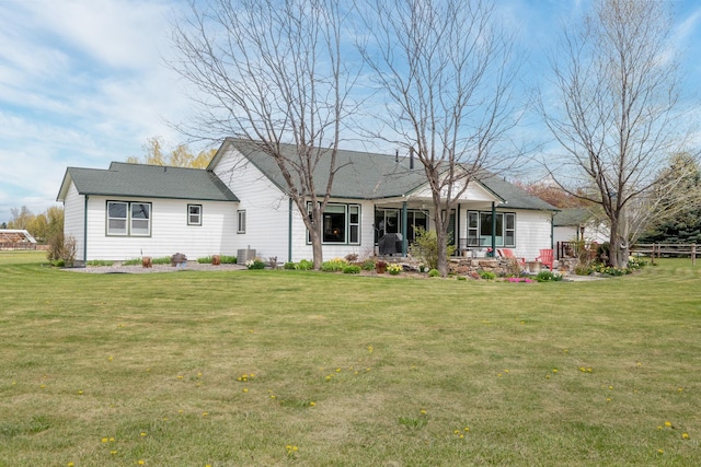 rear view of house featuring a lawn, central AC unit, fence, and a patio