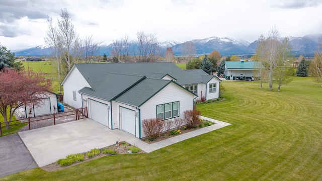 exterior space featuring a front lawn, fence, concrete driveway, an attached garage, and a mountain view